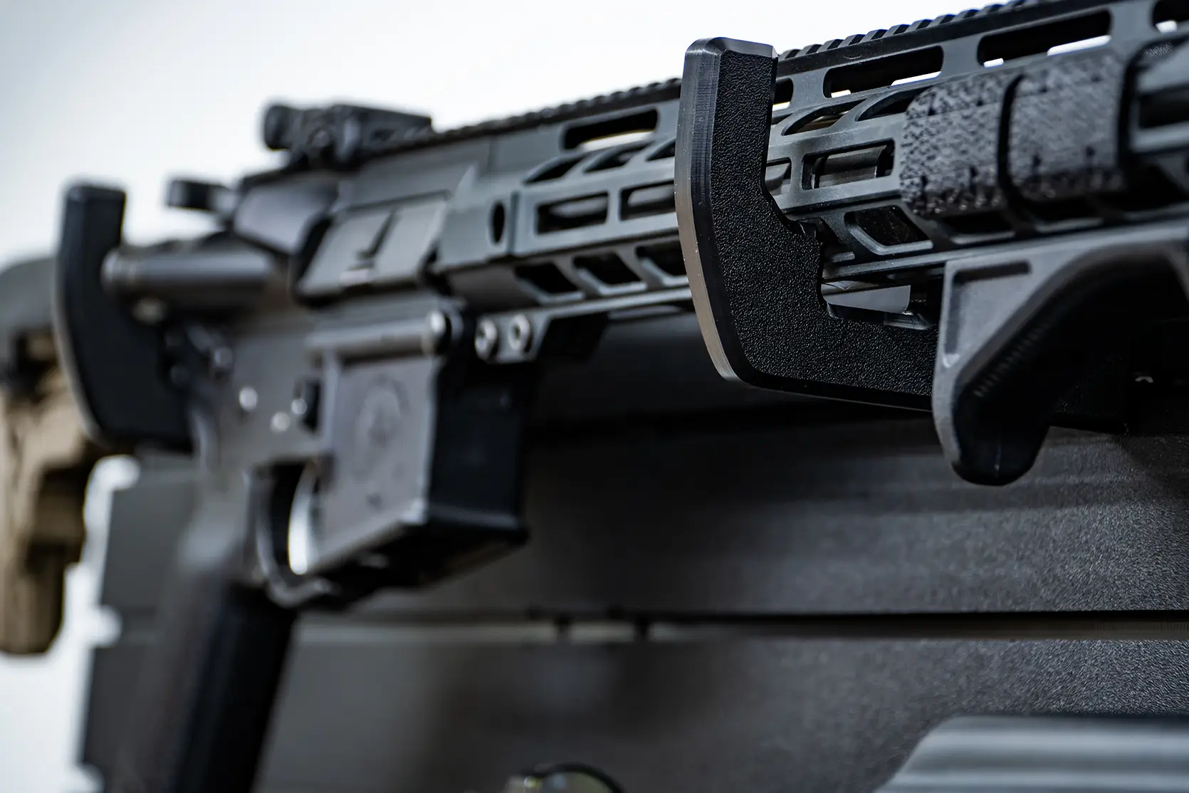 ModWall 9 Gun Combo Pack A close-up view of a black tactical rifle handguard resting securely in a ModWall horizontal rack, showing the smooth, protective finish of the HDPE material.