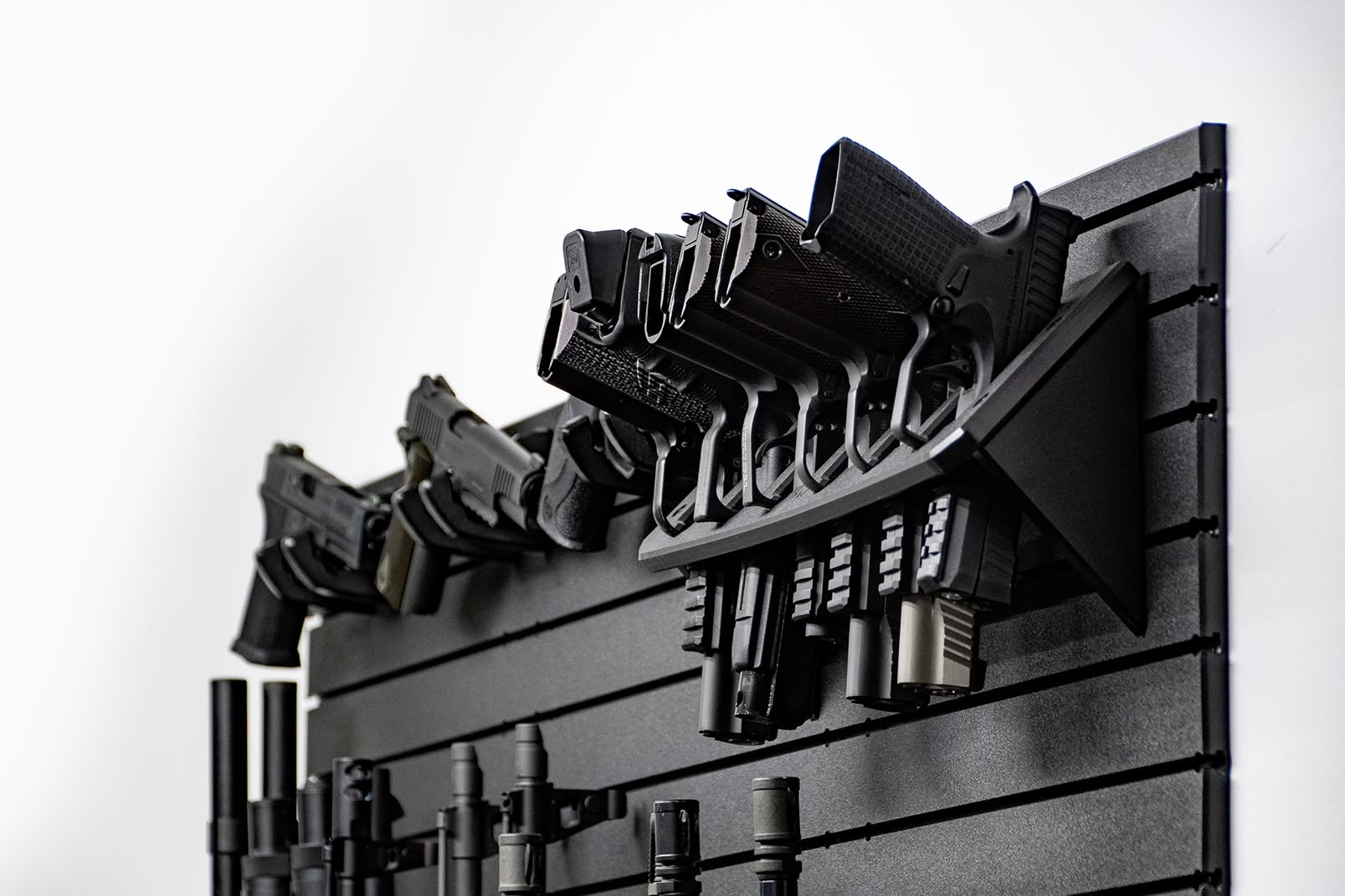 ModWall Compact 21 Gun Package A side-angle view of six handguns held in a vertical high-density rack on a black modular panel. This orientation highlights how the system stores multiple sidearms while maintaining a low profile against the wall.