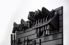 A side-angle view of six handguns held in a vertical high-density rack on a black modular panel. This orientation highlights how the system stores multiple sidearms while maintaining a low profile against the wall.