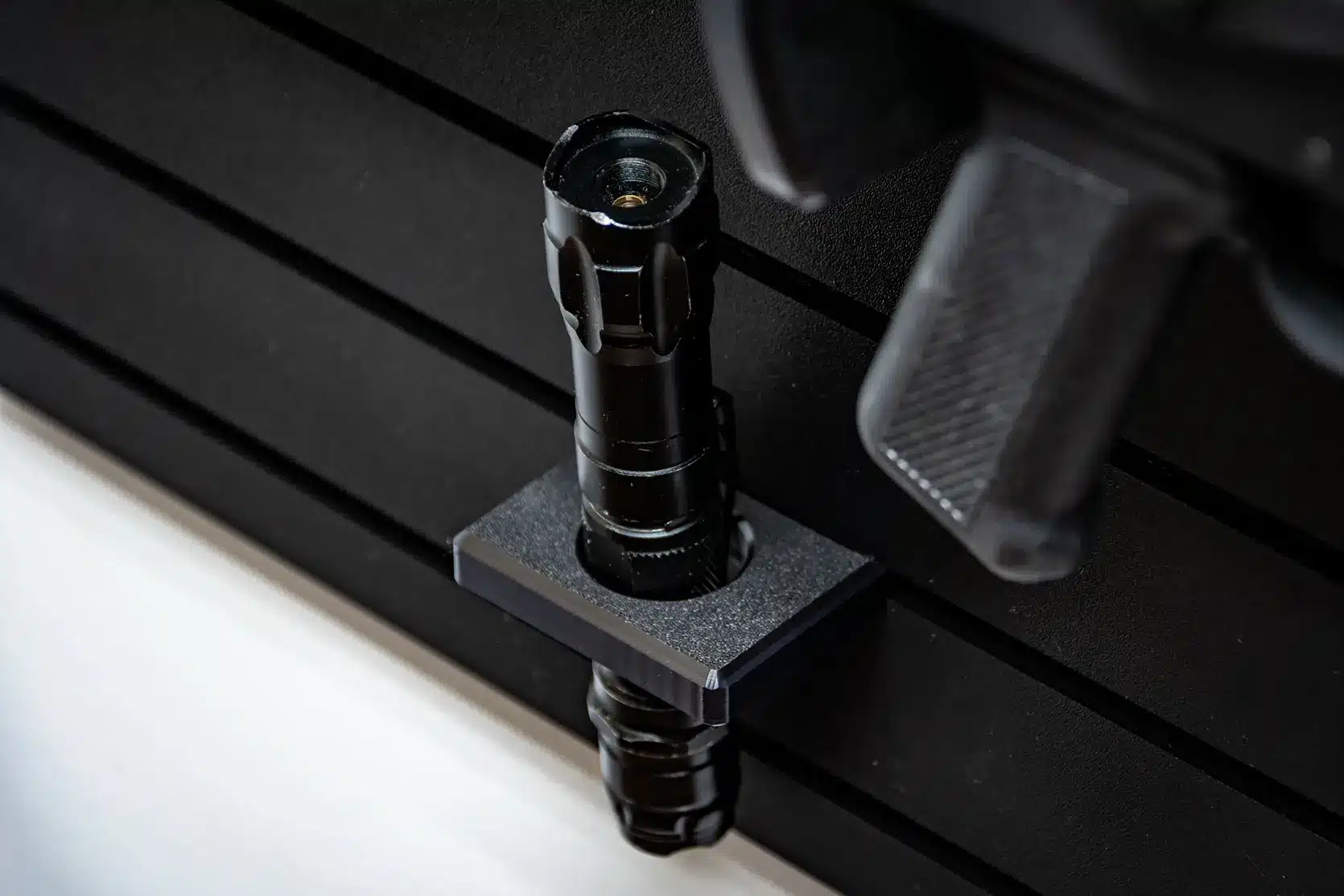 ModWall 9 Gun Combo Pack Close-up of a black tactical flashlight secured in a ModWall flashlight holder on a ModWall panel.