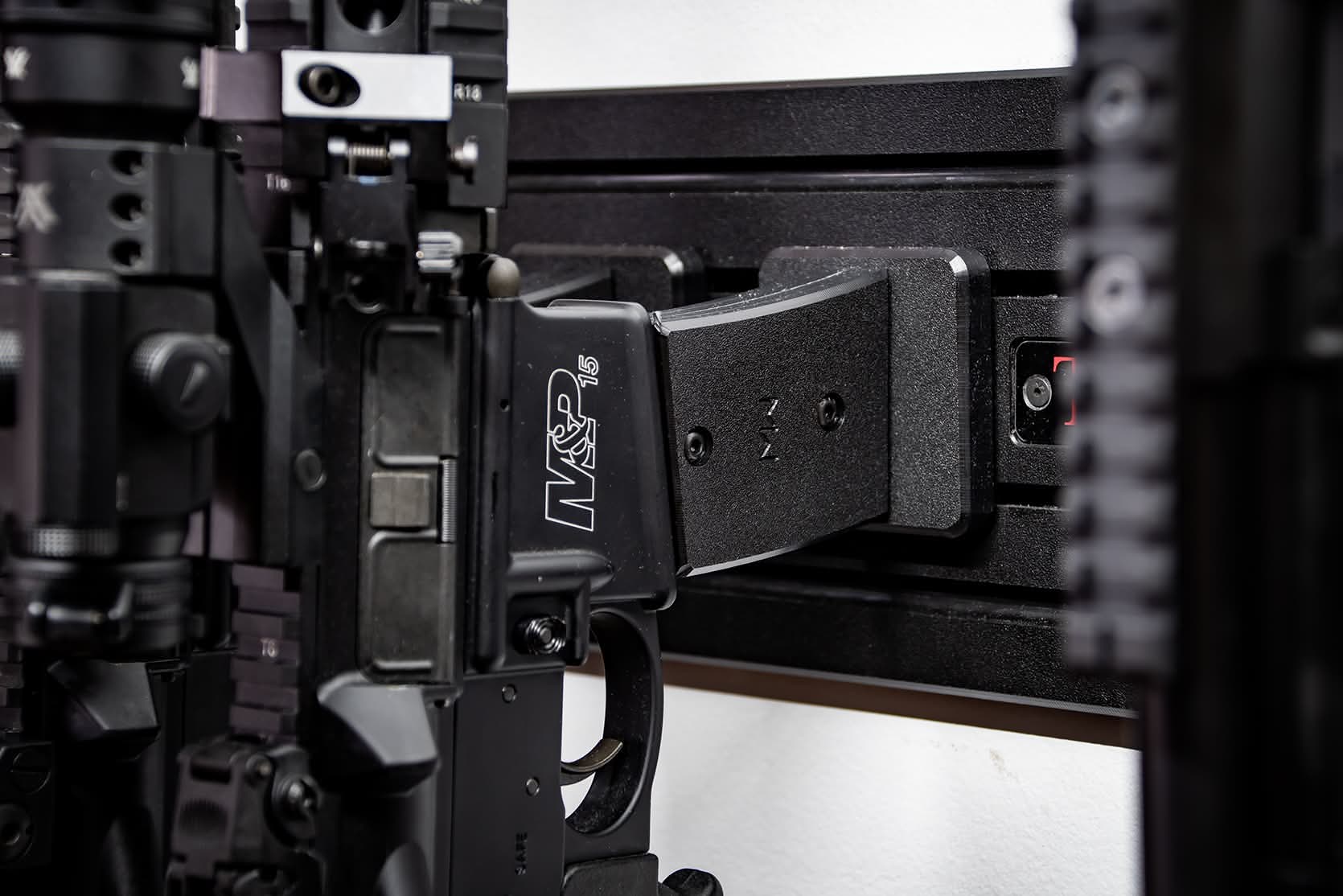 Modwall vertical rifle hangers holding an AR-style rifle by the mag well