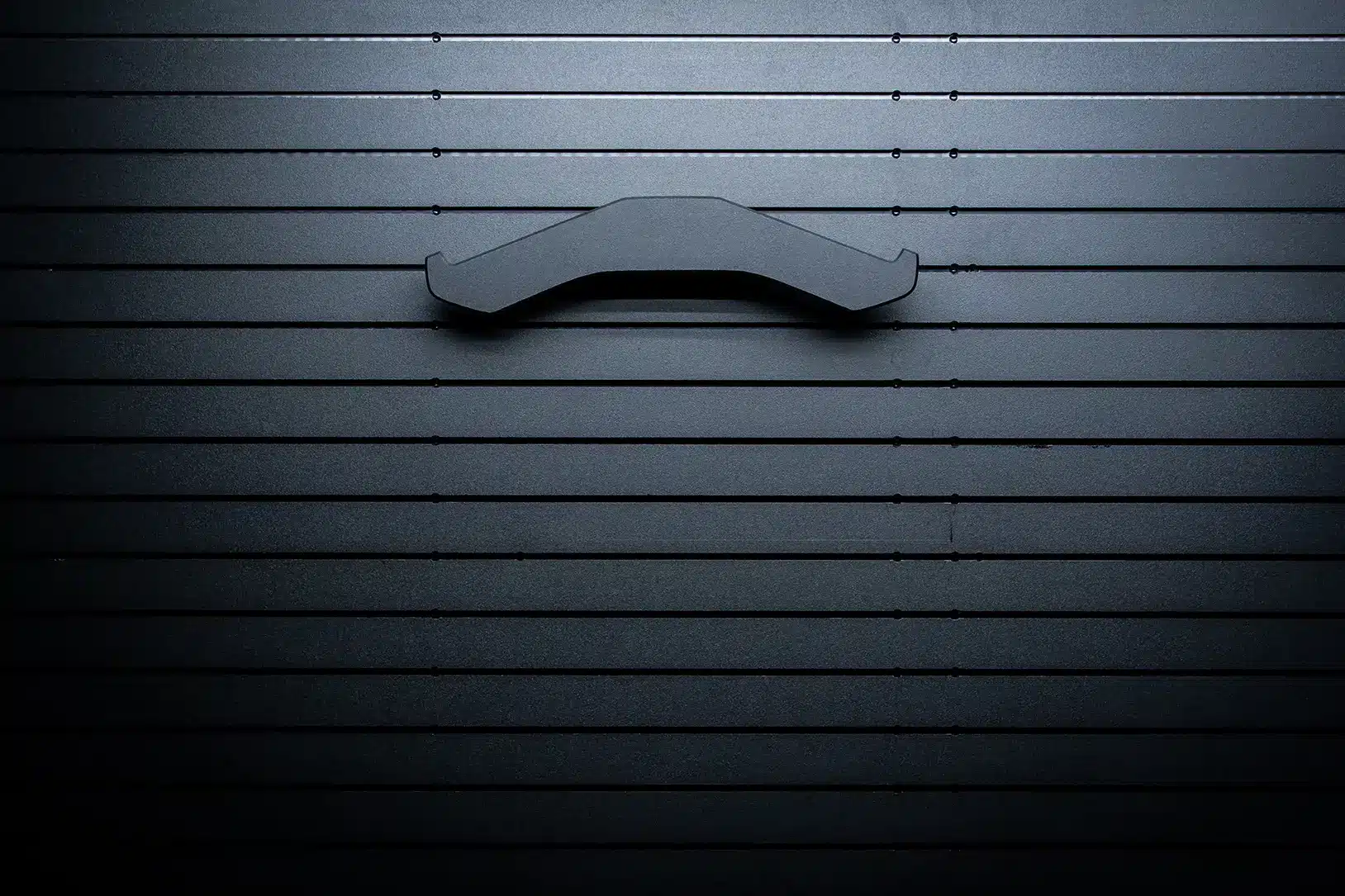 ModWall Vest Hanger A front-view of a wall-mounted vest hanger against a black panel.