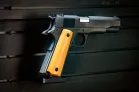 ModWall Pistol Hangers A M1911 pistol mounted by the mag wall on a modular, black gun wall panel with the barrel facing right.