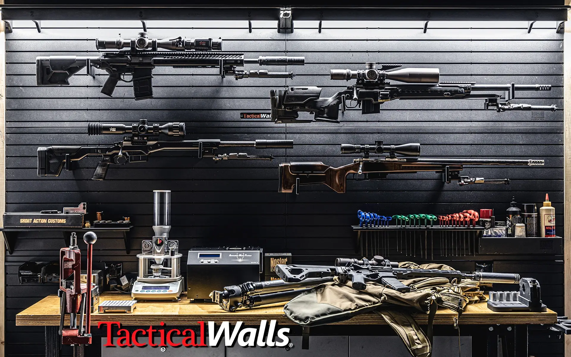 ModWall Panels (48″Wx22″H) A complete gun room and reloading workshop setup featuring Tactical Walls ModWall Panels as the backdrop for displaying multiple long-range rifles horizontally using various mounts. The workbench below is filled with a reloading press, tools, and other gear.