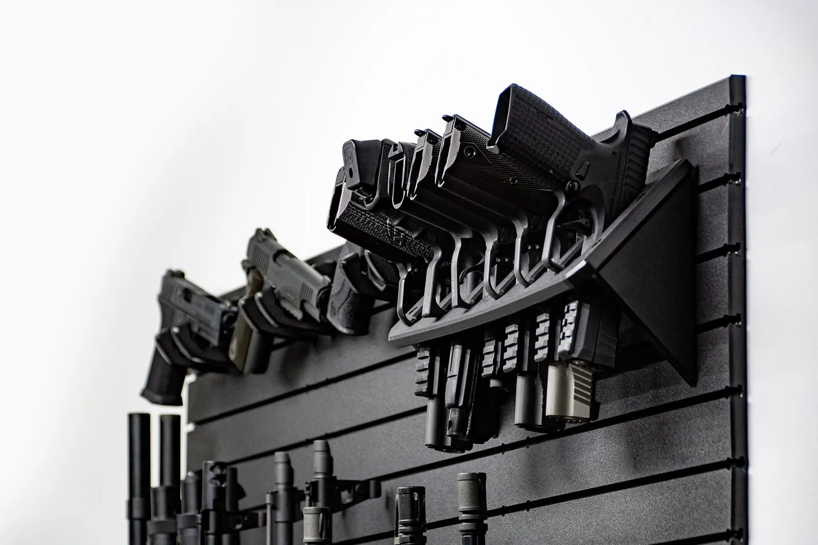 ModWall Compact 21 Gun Package A side-angle view of six handguns held in a vertical high-density rack on a black modular panel. This orientation highlights how the system stores multiple sidearms while maintaining a low profile against the wall.