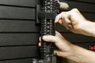 ModWall Strap Blocks A person vertically mounting a rifle to a ModWall strap block using its hook and loop velcro straps.