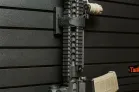 ModWall Strap Blocks A rifle being held vertically flush against a black ModWall panel utilizing two 3x3 velcro strap mounts.