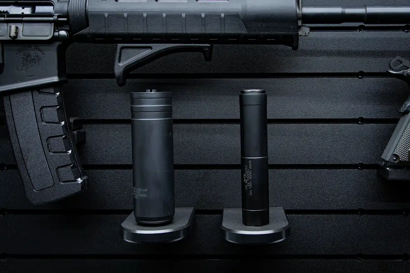 ModWall Suppressor Holder Two black silencers of different sizes stored on wall-mounted pegs.