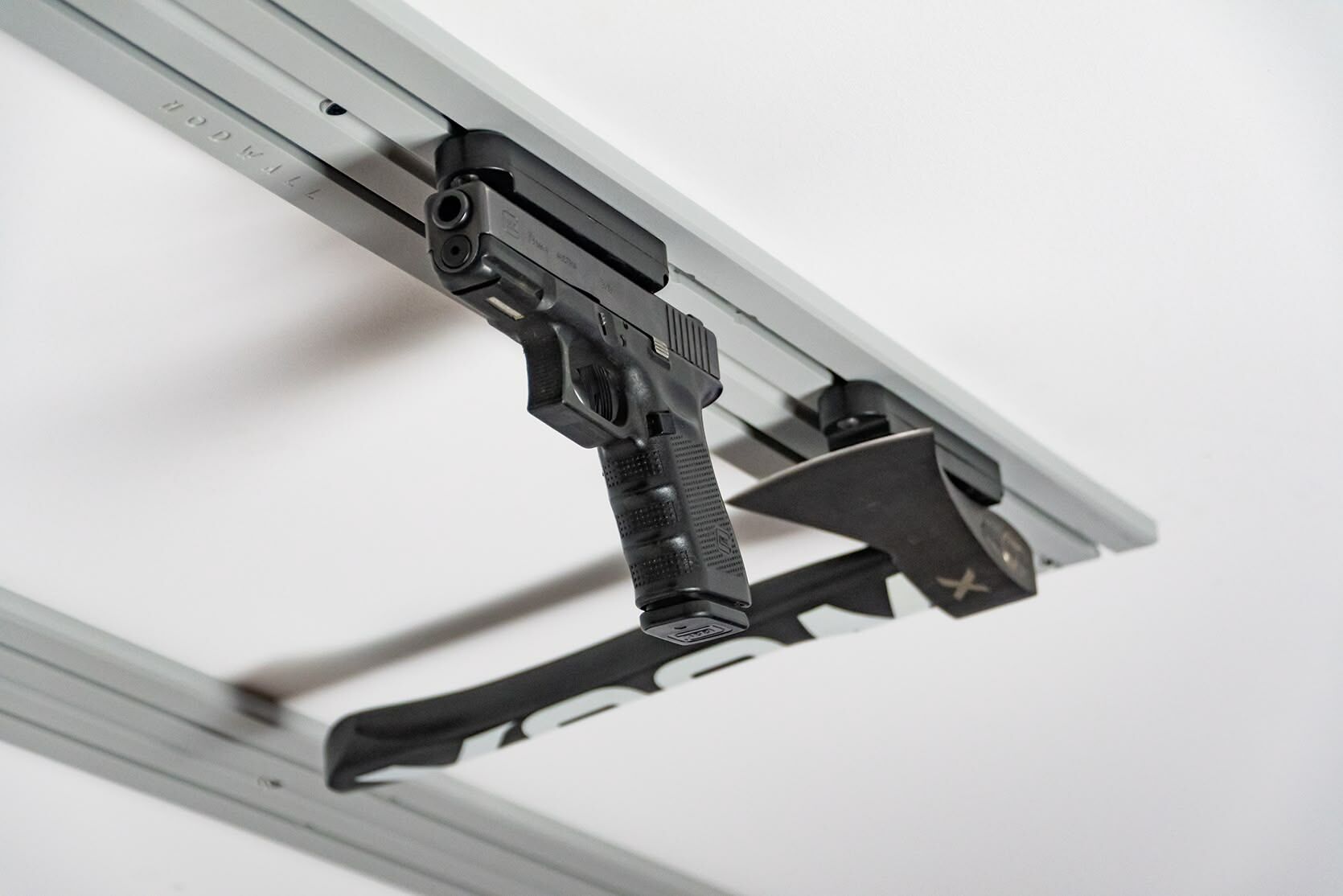 ModWall Ceiling Panel Strip (48″x4″) A handgun and a tactical axe are mounted using specialized modular mounts. This overhead configuration keeps defensive gear organized and accessible while remaining out of the way.
