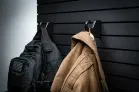 The ModWall Hook A black backpack and beige coat hung against a black panel.