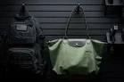 The ModWall Hook A green purse and a black backpack being hung on the ModWall hooks against a ModWall panel.