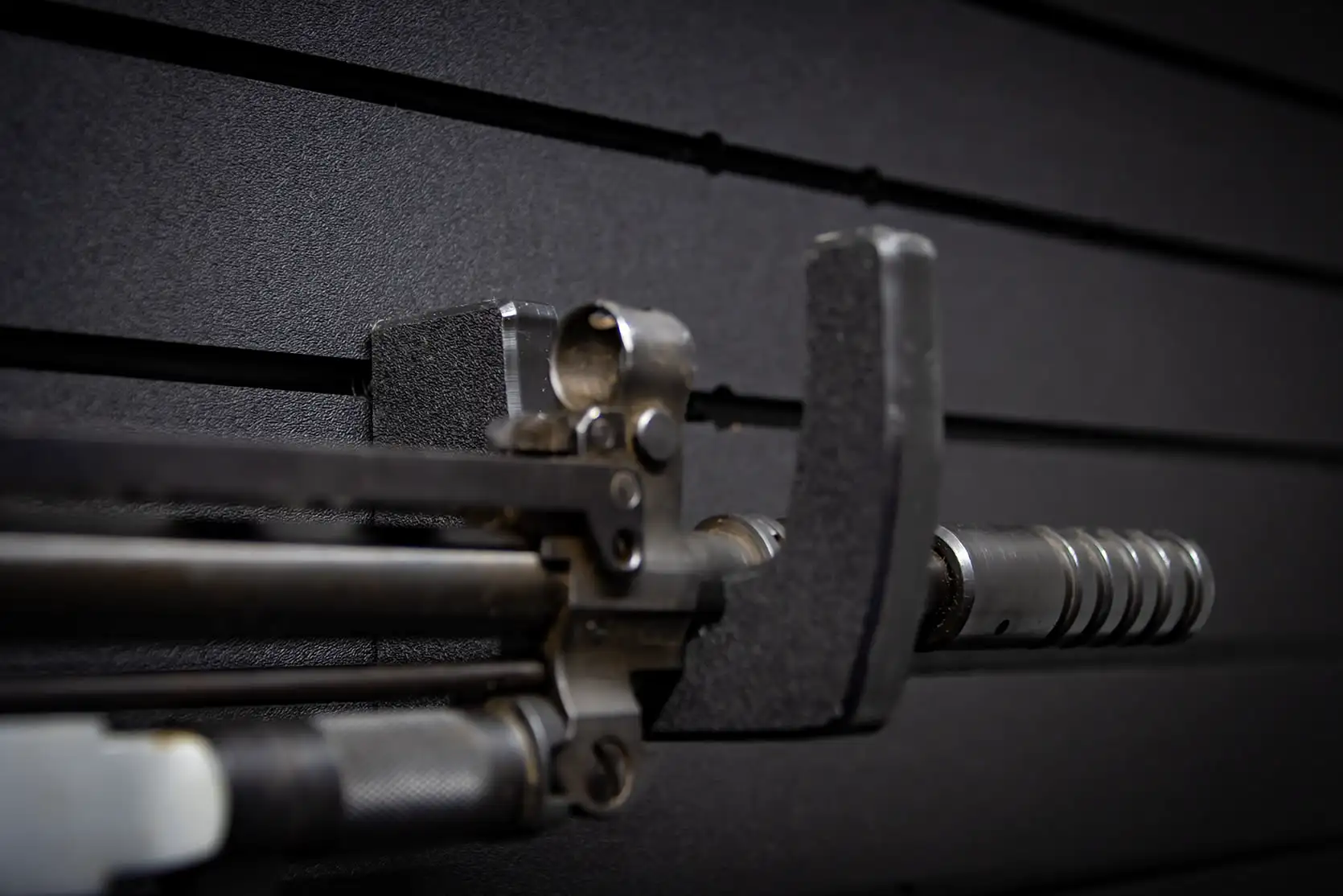 A macro close-up view of a firearm barrel and front sight assembly cradled safely inside a protective, heavy-duty mount.